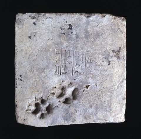 Brick from the ziggurat of Ur, stamped with Ur-Nammu's name, c. 2100 BCE. Two dog's paw marks are seemingly-accidentally marked on one side. Image courtesy British Museum.