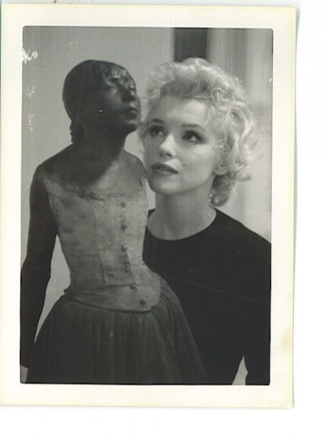 Marilyn Monroe looking at a statue of Edgar Degas' "Little Dancer of Fourteen Years." Photo taken at William Goetz's house, 1956